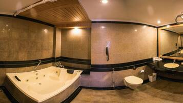A modern bathroom with a large bathtub, a separate toilet, and a vanity with a mirror.