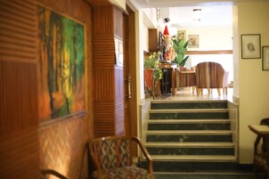 A staircase leading to a dining area with striped chairs and a table with a red cone on it.
