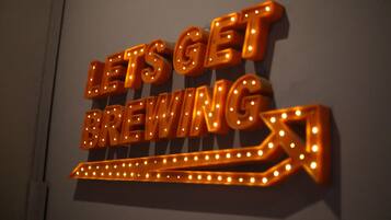 Un letrero de neón con el texto "LET'S GET BREWING" sobre un fondo oscuro.
