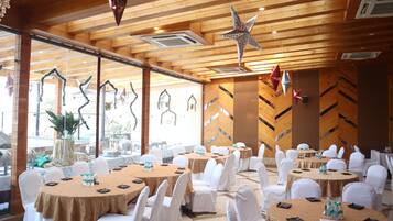 A conference room with round tables, white chairs, and a wooden ceiling.