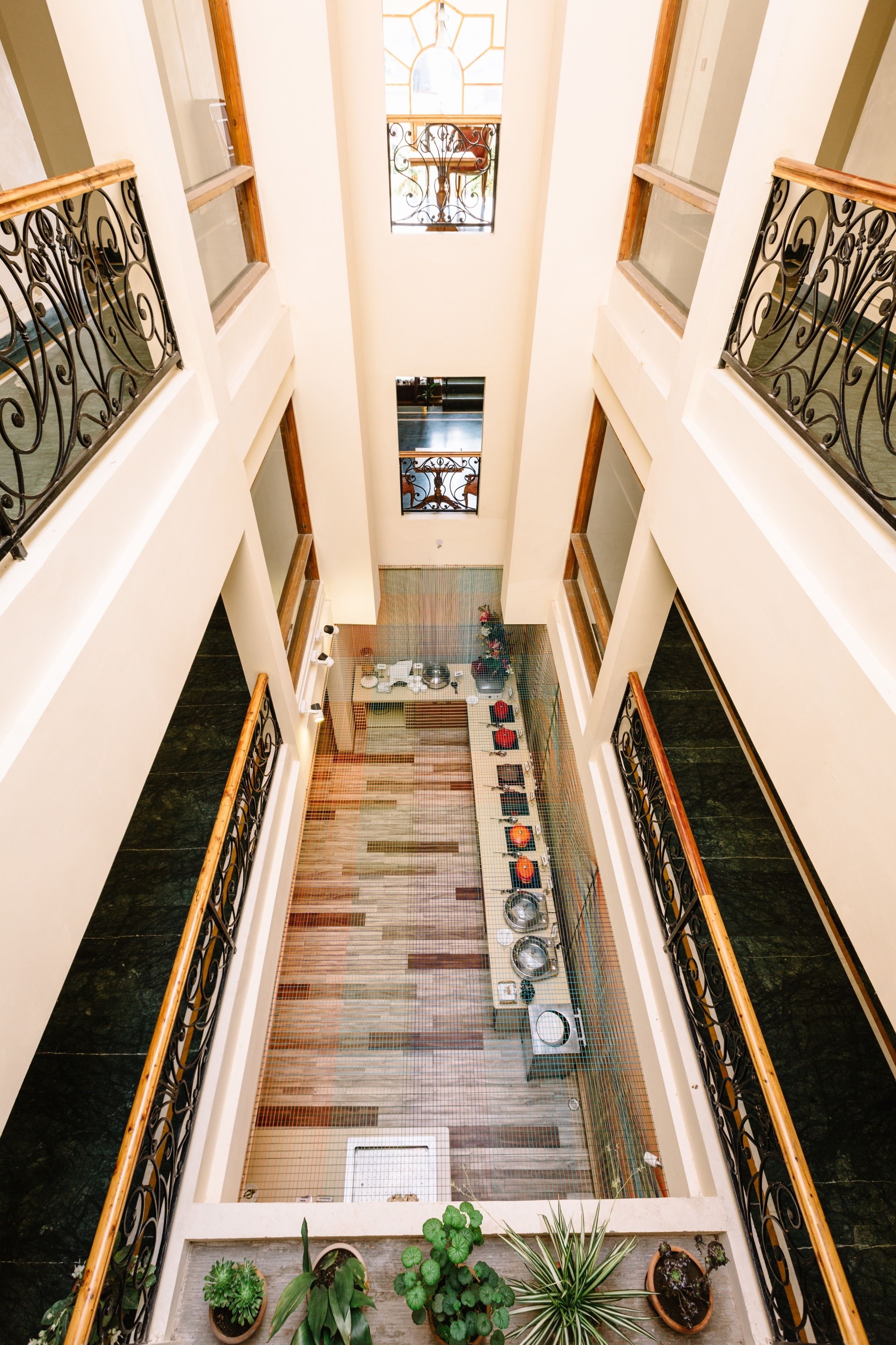Ein Atrium mit hohen Decken, einem offenen zentralen Bereich, dekorativen Eisenengelgitter und Blumentöpfen.