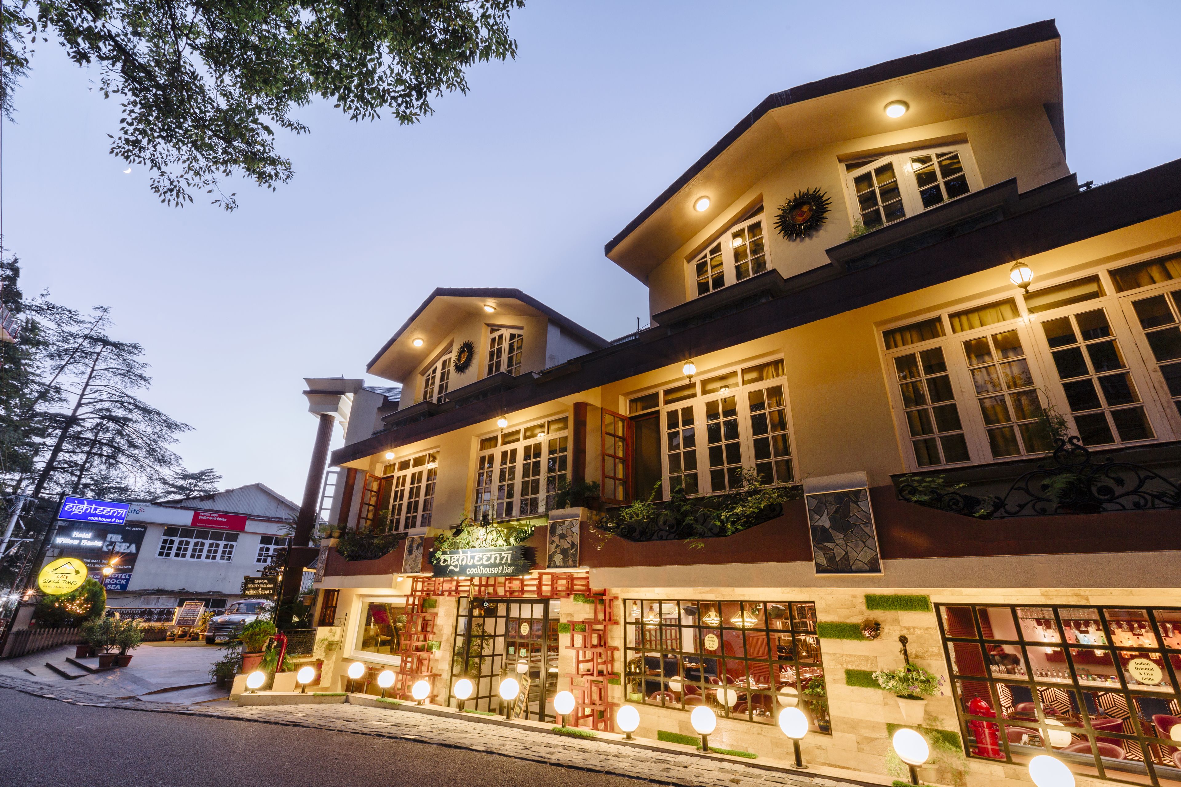 A hotel with multiple floors, large windows, and outdoor seating areas.