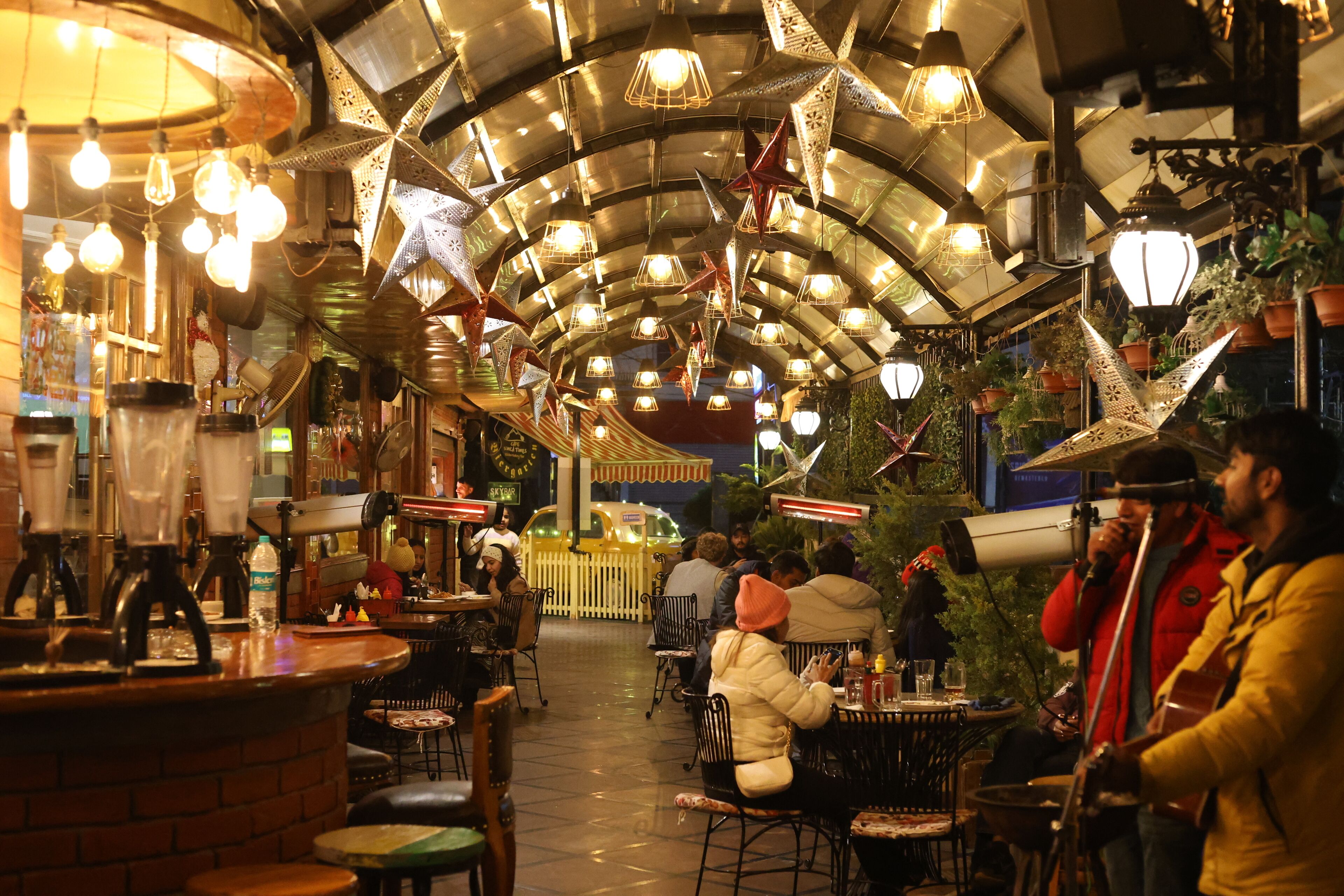An indoor dining area with tables and chairs, a bar counter, and hanging decorative lights.
