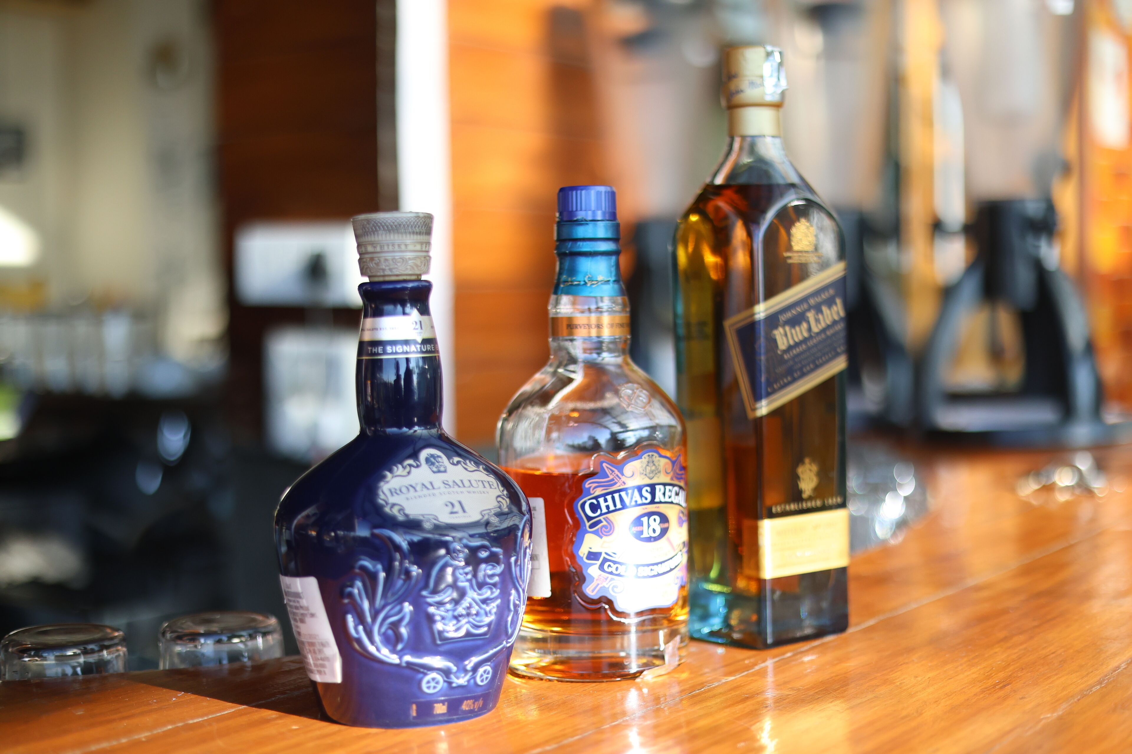 Three bottles of liquor on a bar counter.