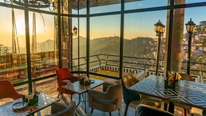 A restaurant with a terrace, tables, chairs, and a view of a cityscape. - Hotel Willow Banks, Mall Road Shimla (Shimla)