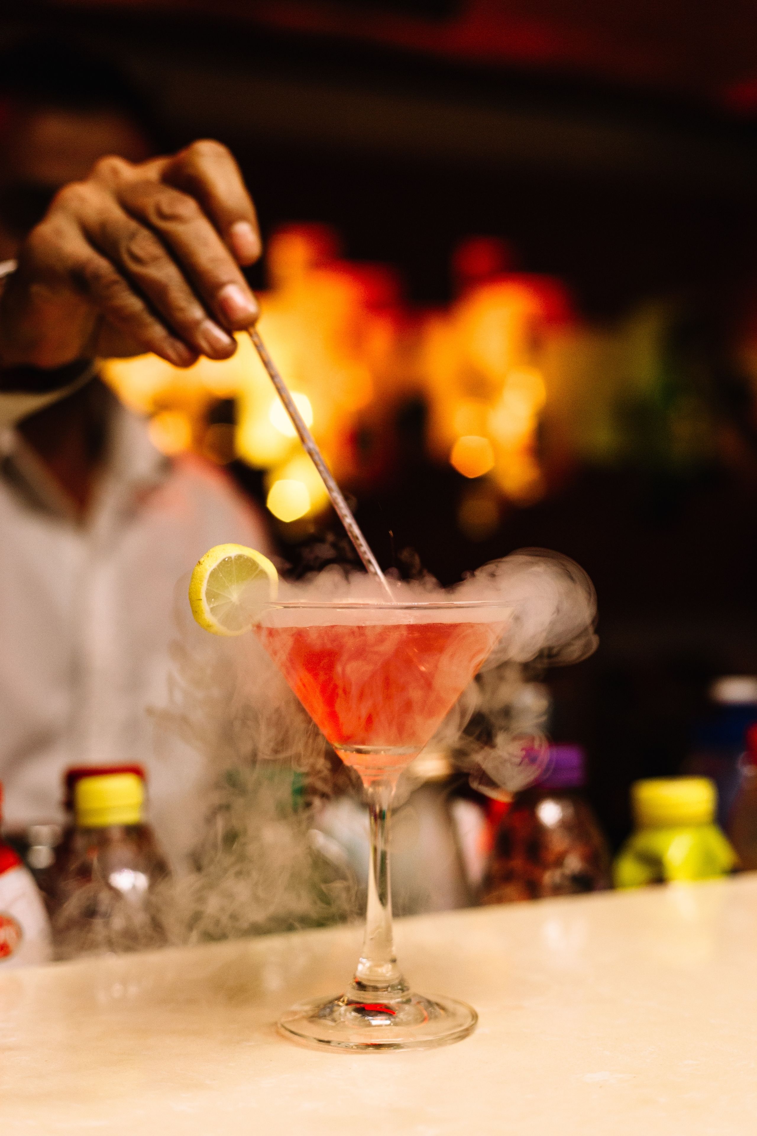 Cóctel con una rodaja de limón y humo, servido en una copa de martini.