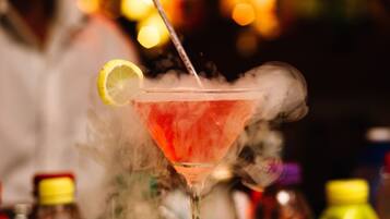 A cocktail with a lemon garnish and smoke, served in a martini glass.