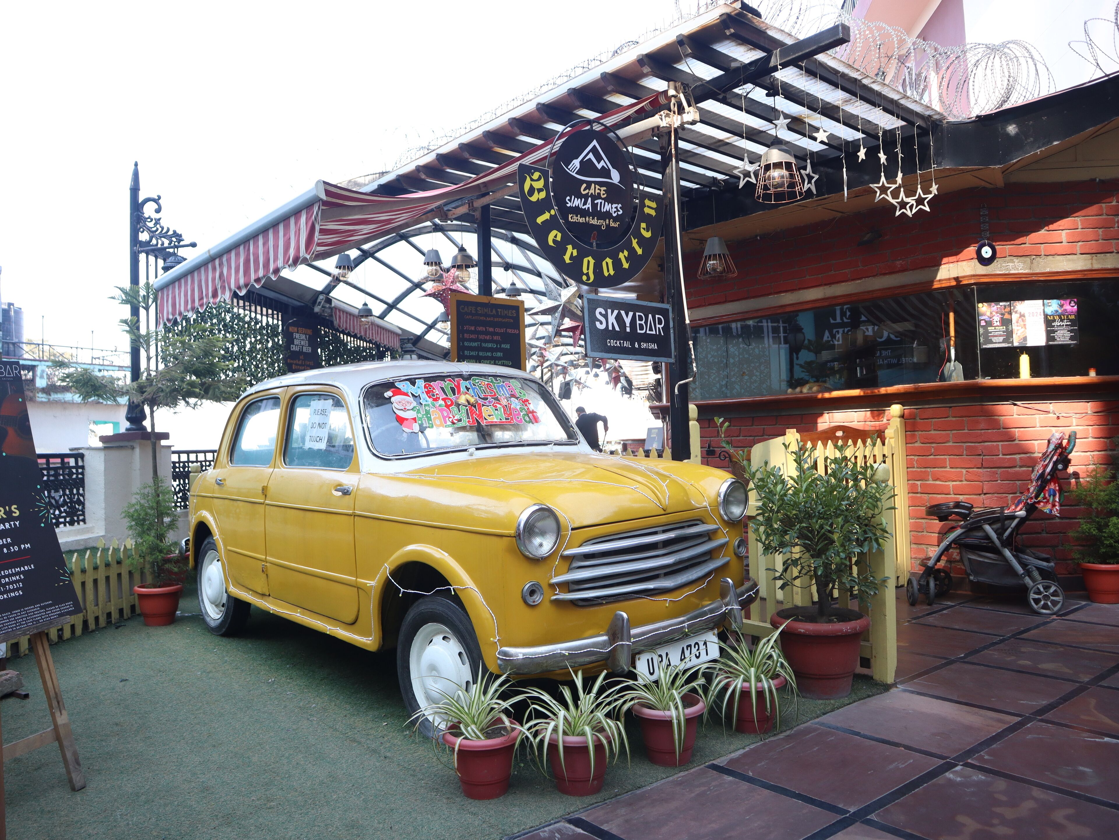 Une voiture ancienne jaune est garée devant un café, et une enseigne indique « SKYBAR ».