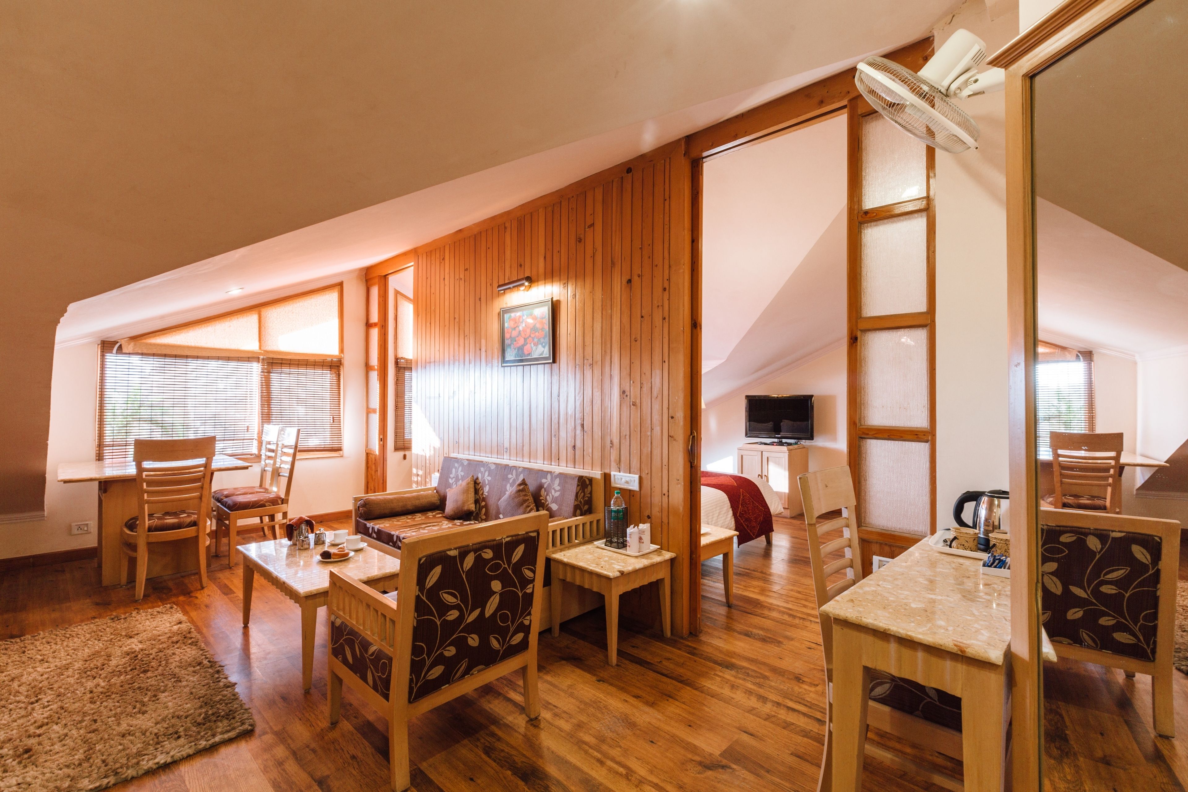 A cozy loft-style room with wooden floors, a sofa, a dining table, and a TV.
