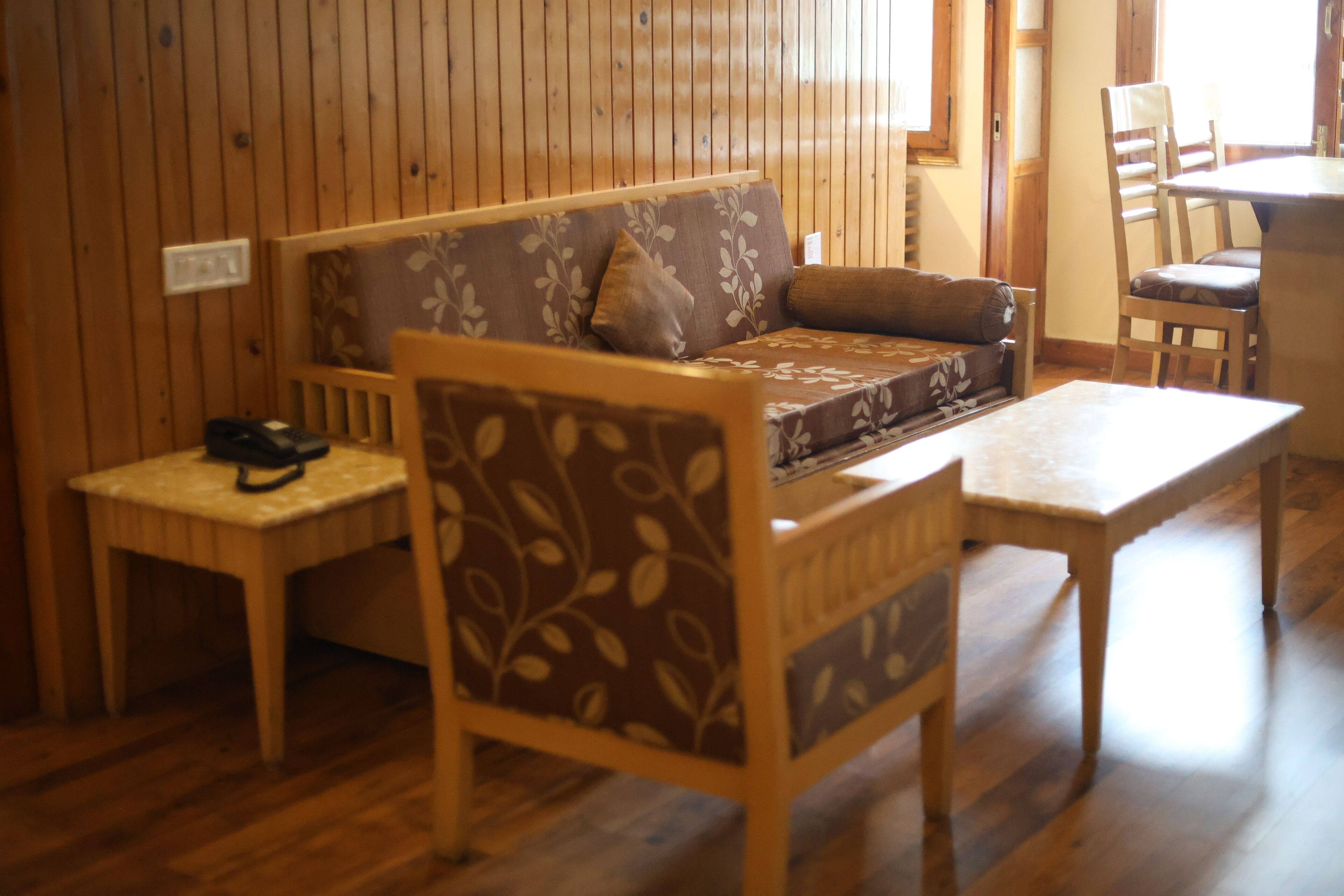 A wooden-floored room with a sofa, a small table, and a chair.