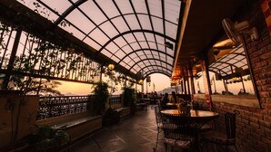 An outdoor café with a glass roof, brick walls, and potted plants. - Hotel Willow Banks, Mall Road Shimla (Shimla)