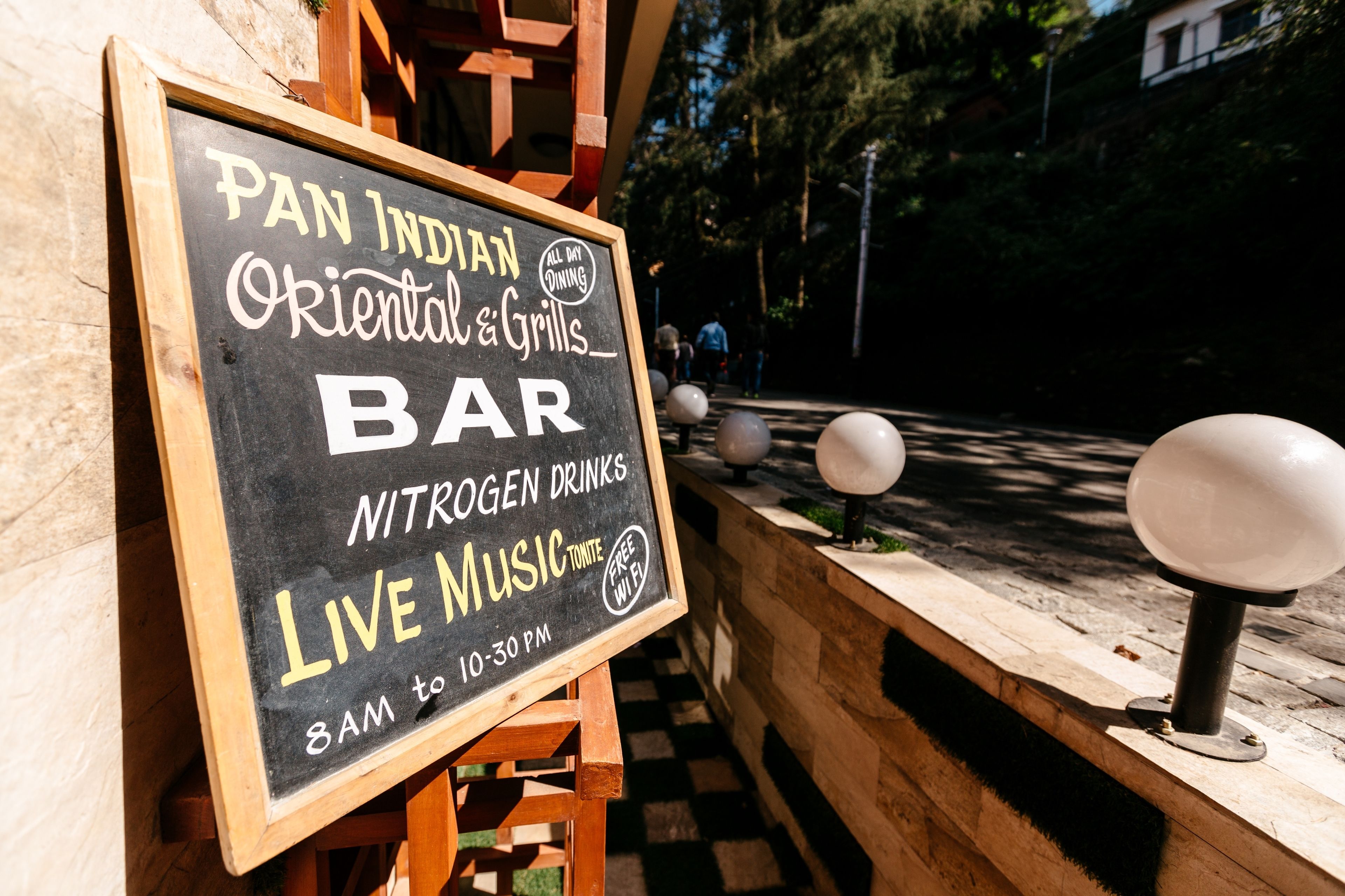 A chalkboard sign advertising a Pan Indian restaurant with a bar, offering nitrogen drinks, live music, and free Wi-Fi.