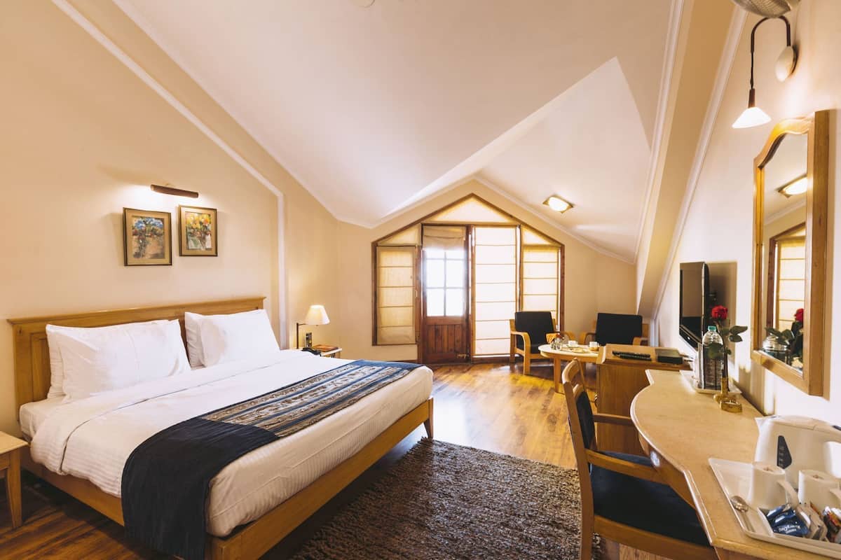 Ein Hotelzimmer mit Bett, Schreibtisch, Stuhl und einem großen Fenster.