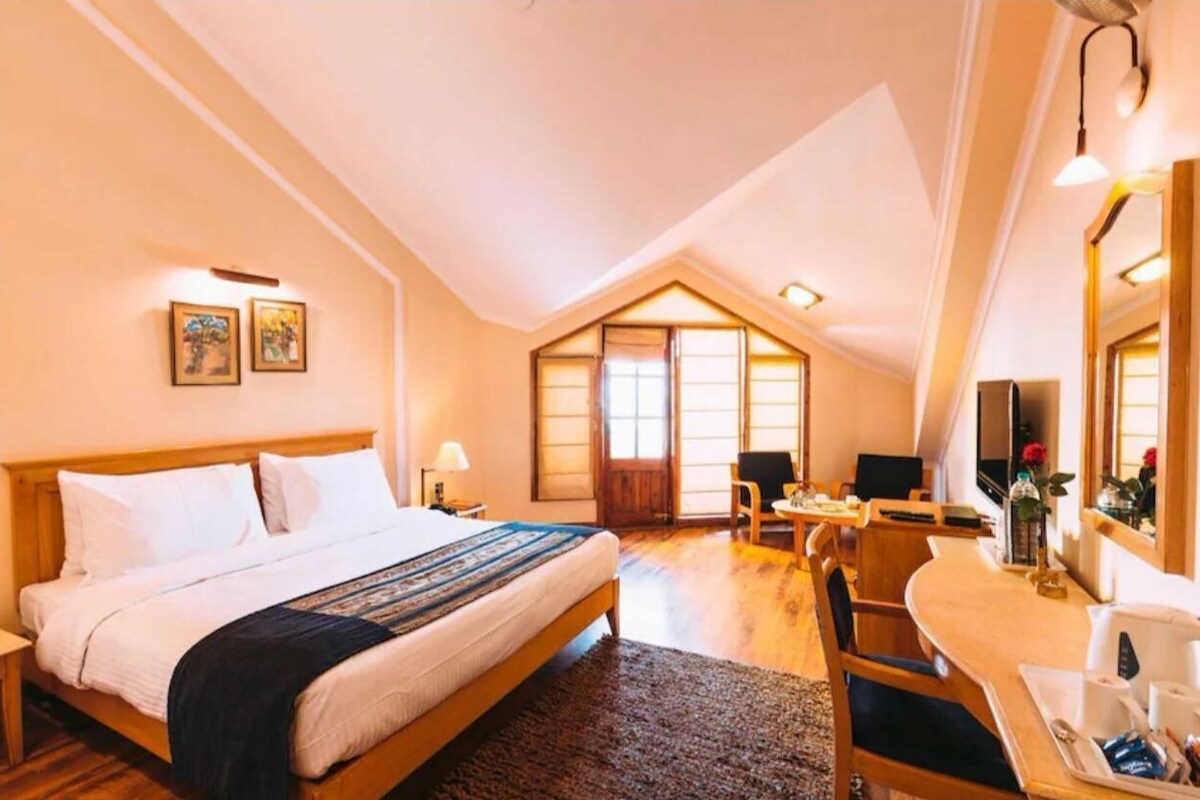 A bedroom with a bed, a desk, a chair, a mirror, and a window.