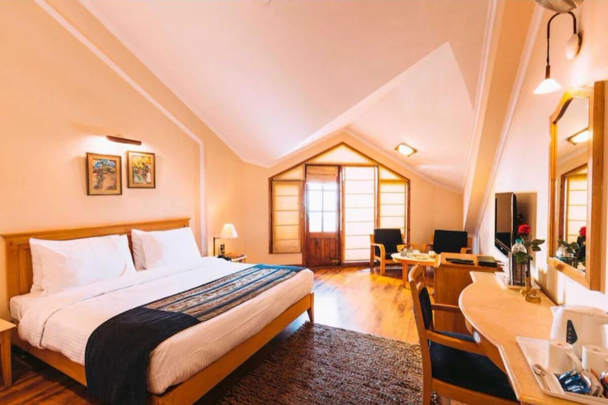 A bedroom with a bed, a desk, a chair, a mirror, and a window.