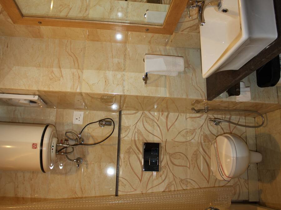 A bathroom with a marble floor, a white sink, a mirror, a towel dispenser, and a toilet.