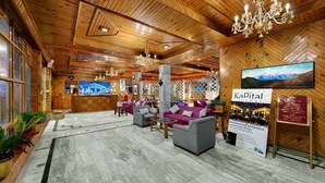 A wooden interior with a reception desk, seating area, and a sign for Kapita Lounge. - Bravia Hotel Manali Inn (Manali)