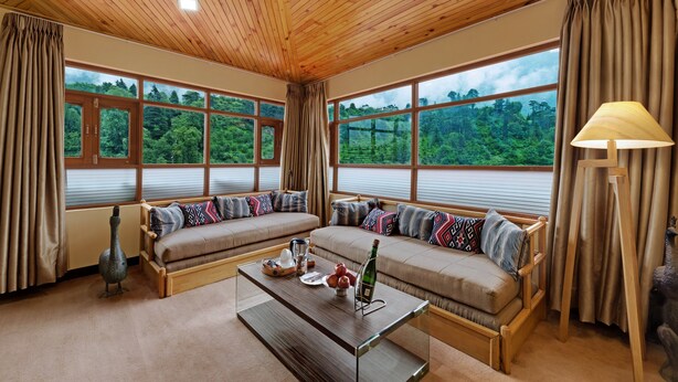 A cozy room with large windows, a sofa set, a coffee table, and a lamp. - Bravia Hotel Manali Inn (Manali)