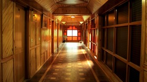A wooden hallway with a herringbone floor, wooden walls, and large windows with red frames. - Bravia Hotel Manali Inn (Manali)