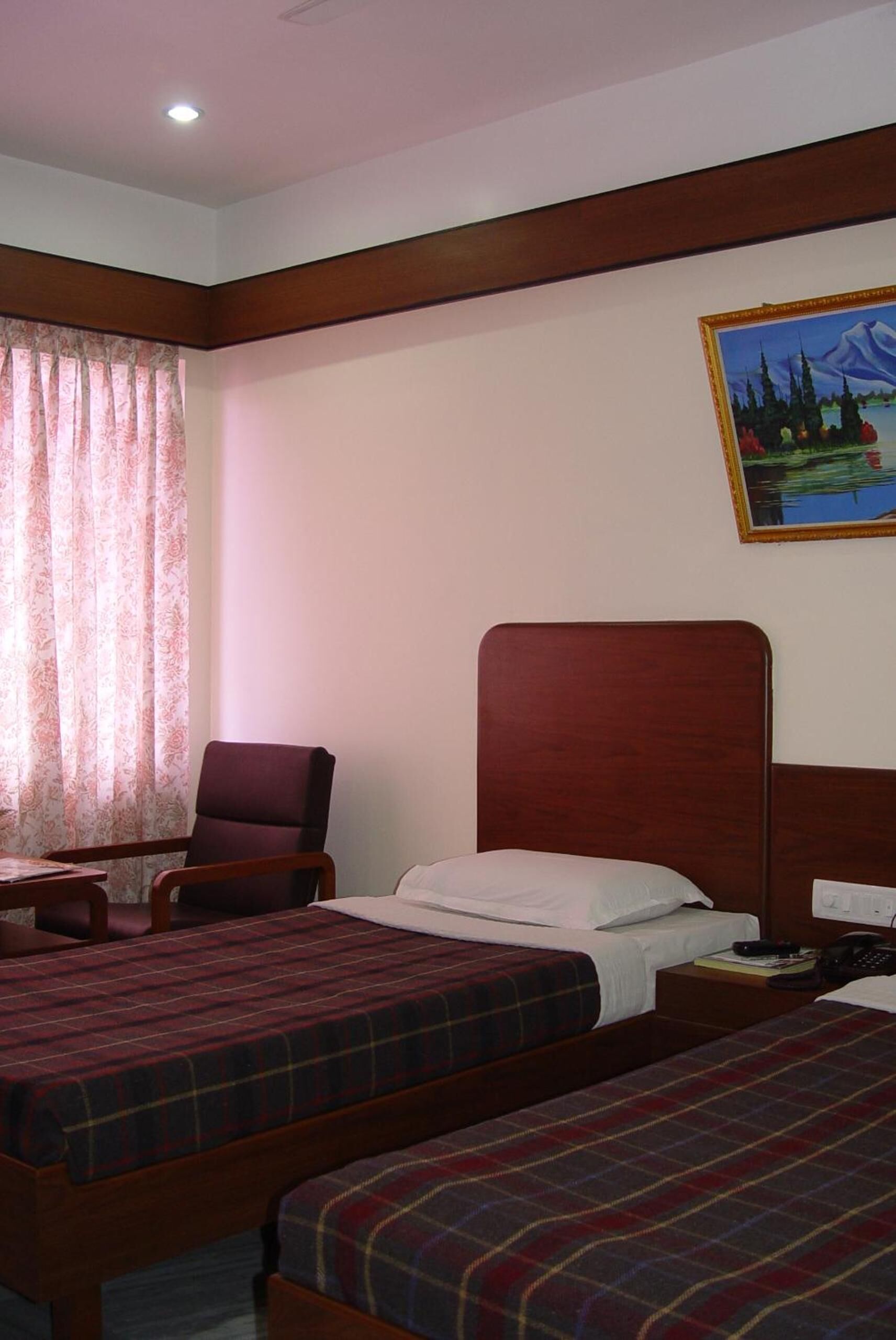 Une chambre d’hôtel avec deux lits, une chaise, un bureau et un tableau au mur.