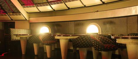 A restaurant with booths and a high ceiling with patterned lights.