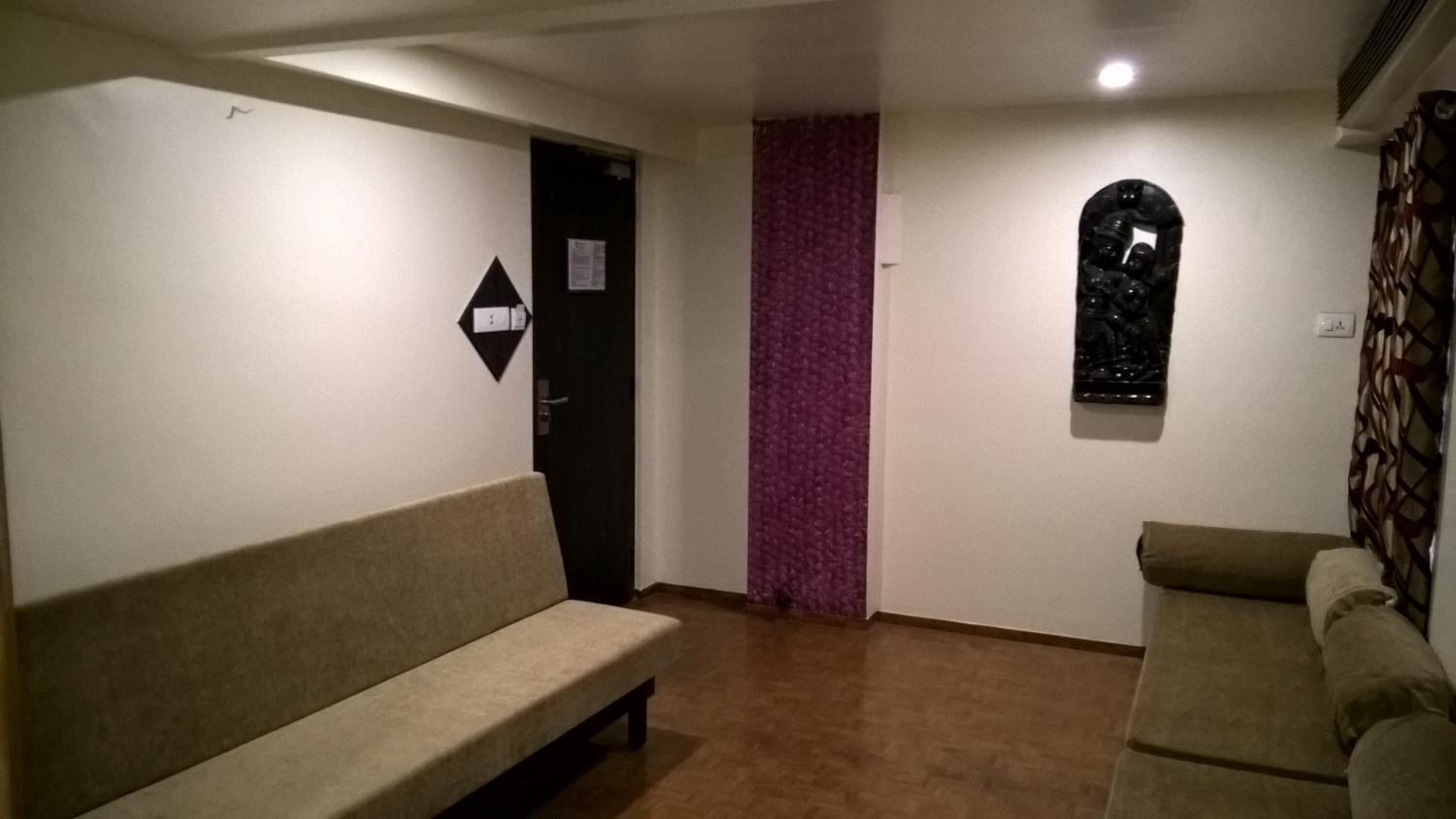 Une pièce avec un canapé beige, un mur à motifs, une porte et une fenêtre.
