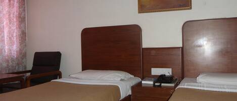 Una camera d'albergo con due letti di legno, una scrivania, una sedia e un quadro appeso al muro.