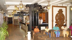 A lobby with seating areas, a reception desk, and a decorative statue. - Hotel Supreme (Madurai)