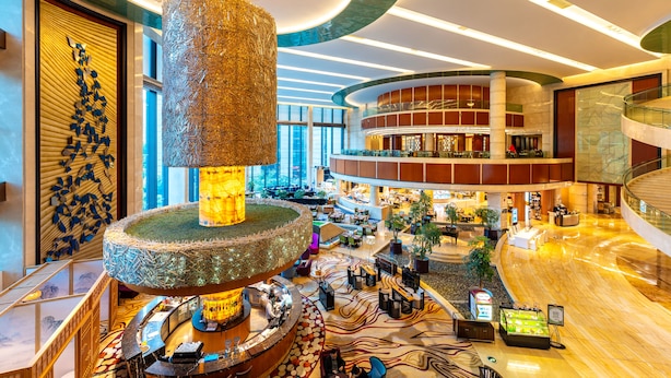 A spacious lobby with a central decorative fountain, multiple seating areas, and a modern architectural design.