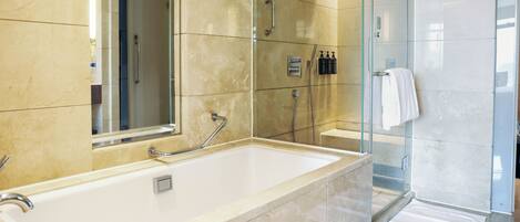 A modern bathroom with a large bathtub, a glass shower enclosure, and a mirror.
