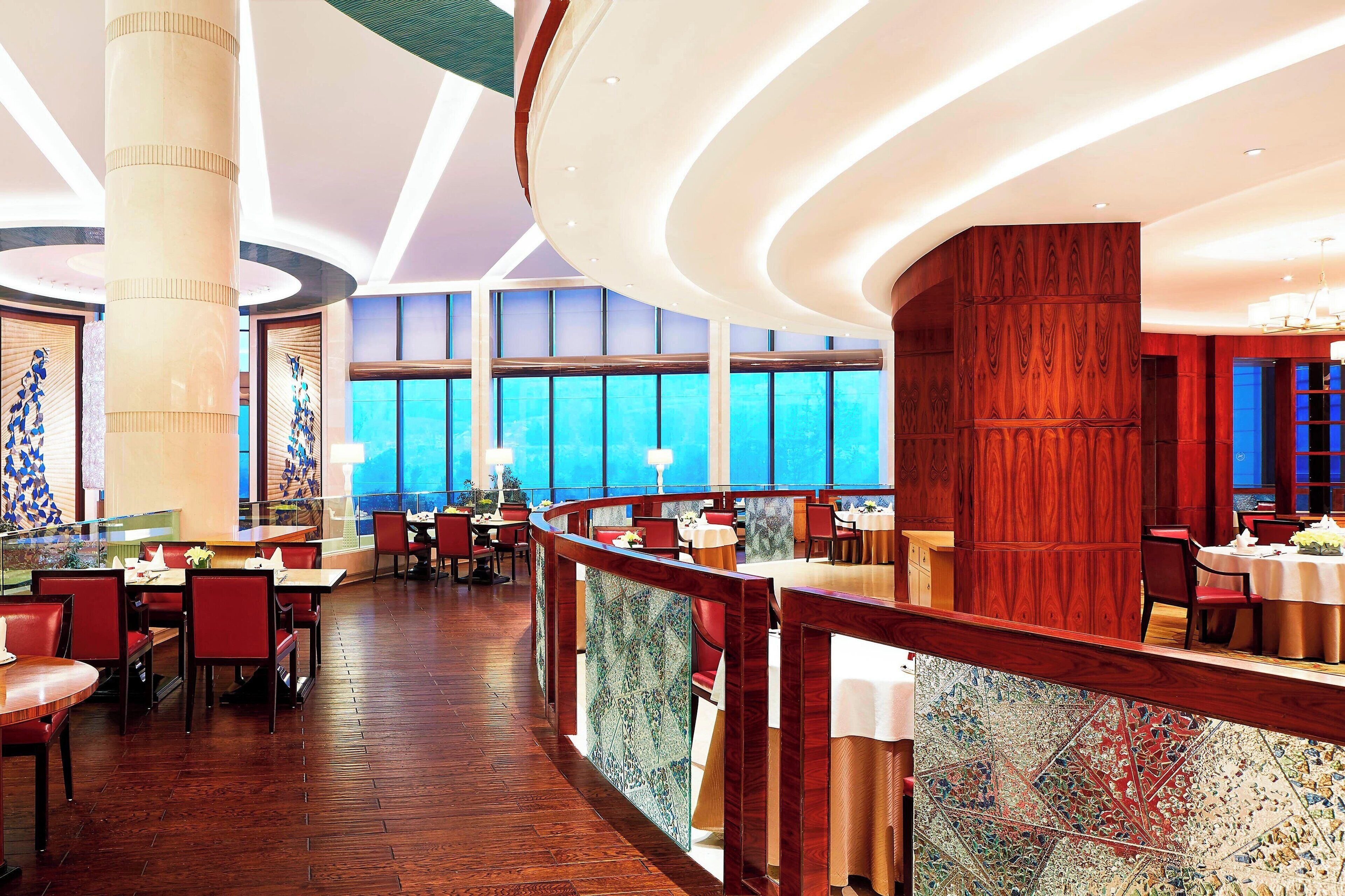A spacious restaurant with high ceilings, large windows, and a wooden interior.
