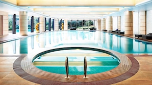 A large indoor swimming pool with clear water, surrounded by columns and large windows.