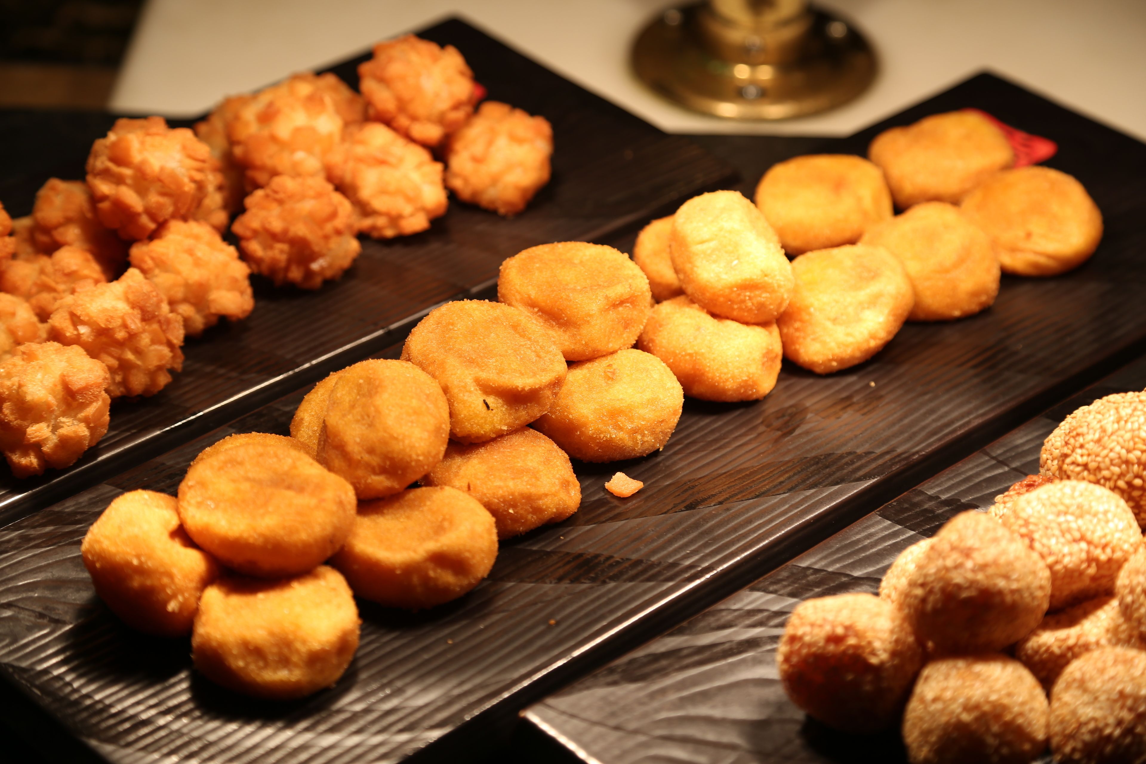Variedad de masas fritas dispuestas sobre una bandeja de madera oscura.