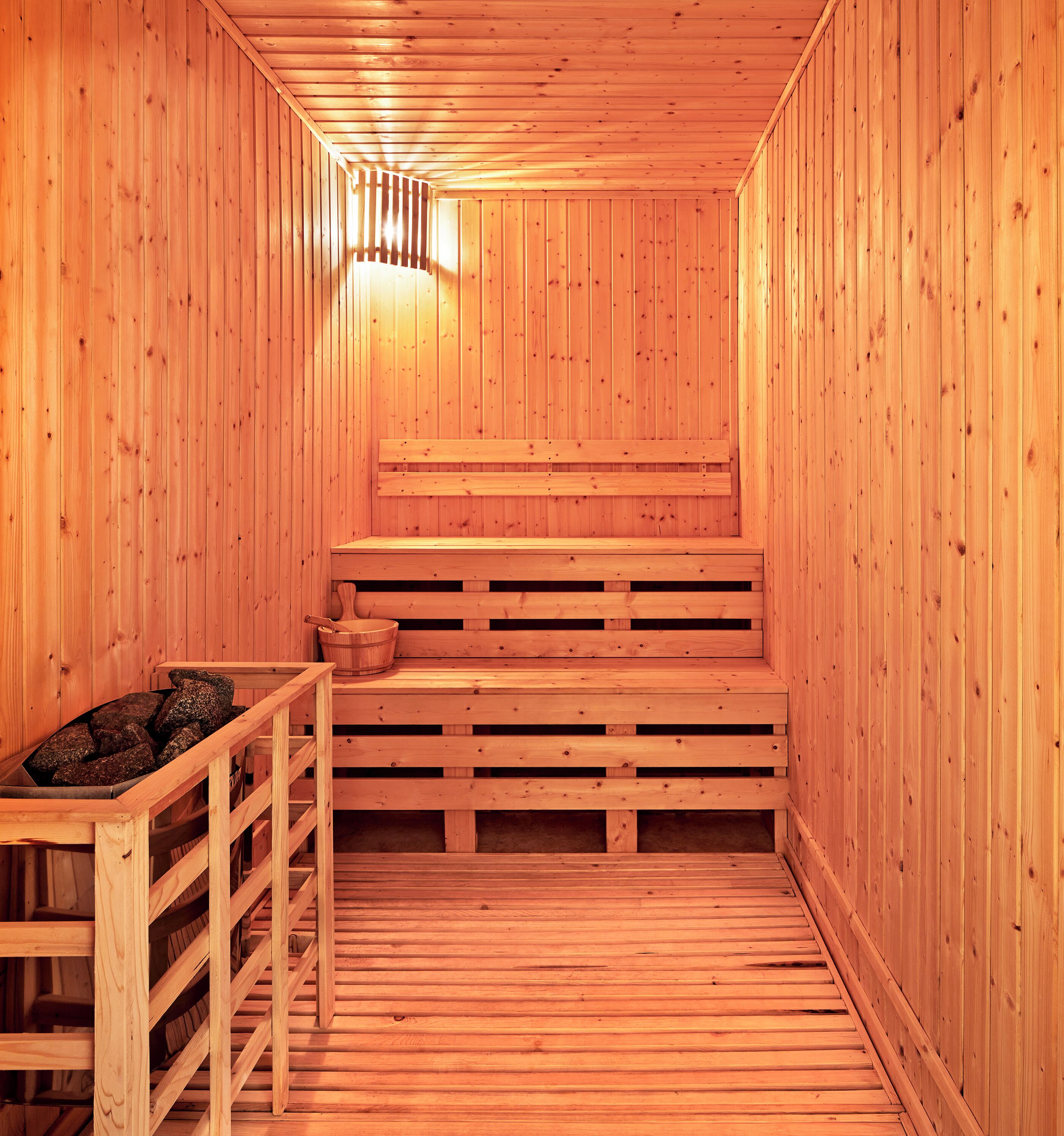 A wooden sauna with benches and a stone basin.