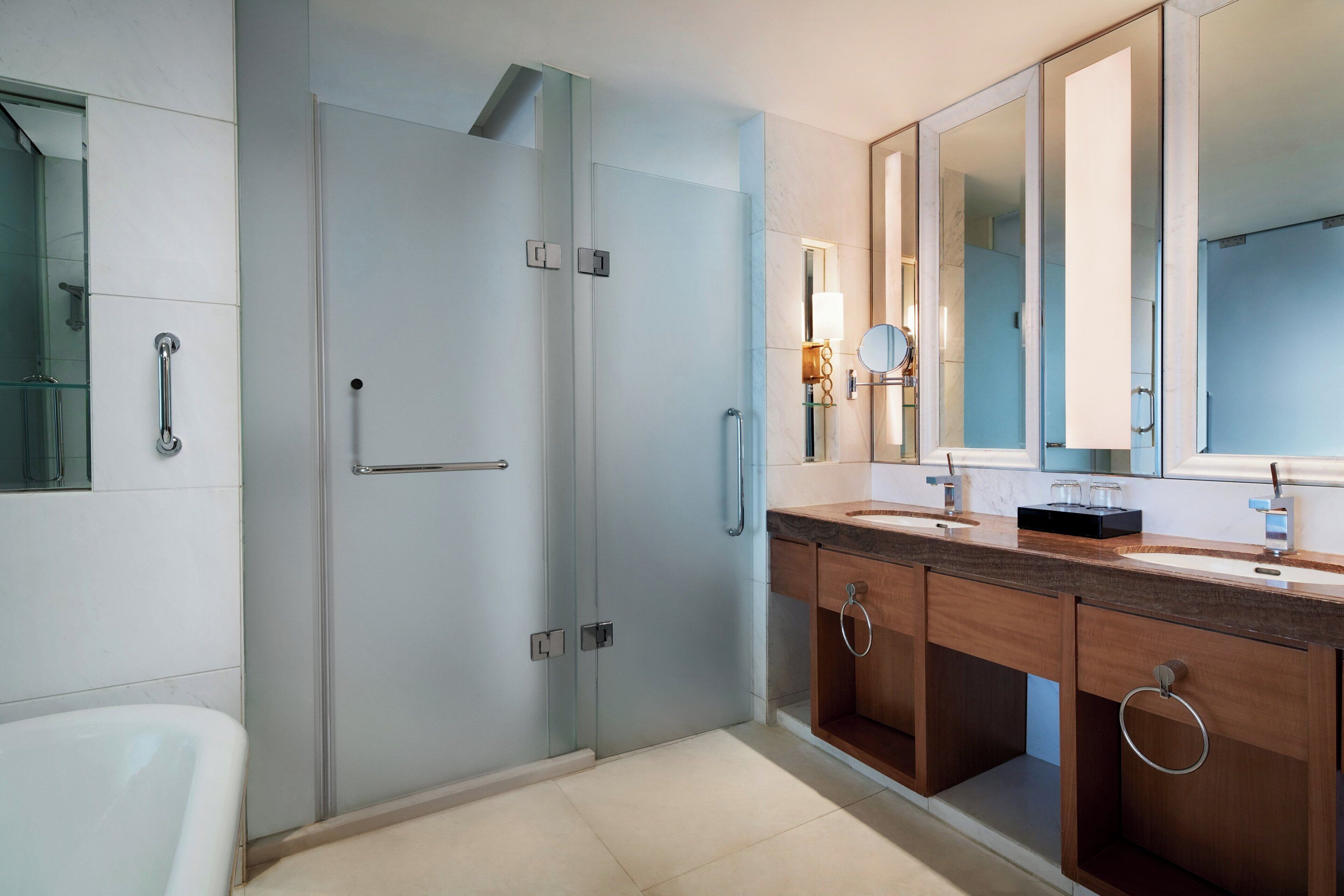 A modern bathroom with a glass shower enclosure, a double sink vanity, and a large mirror above the vanity.
