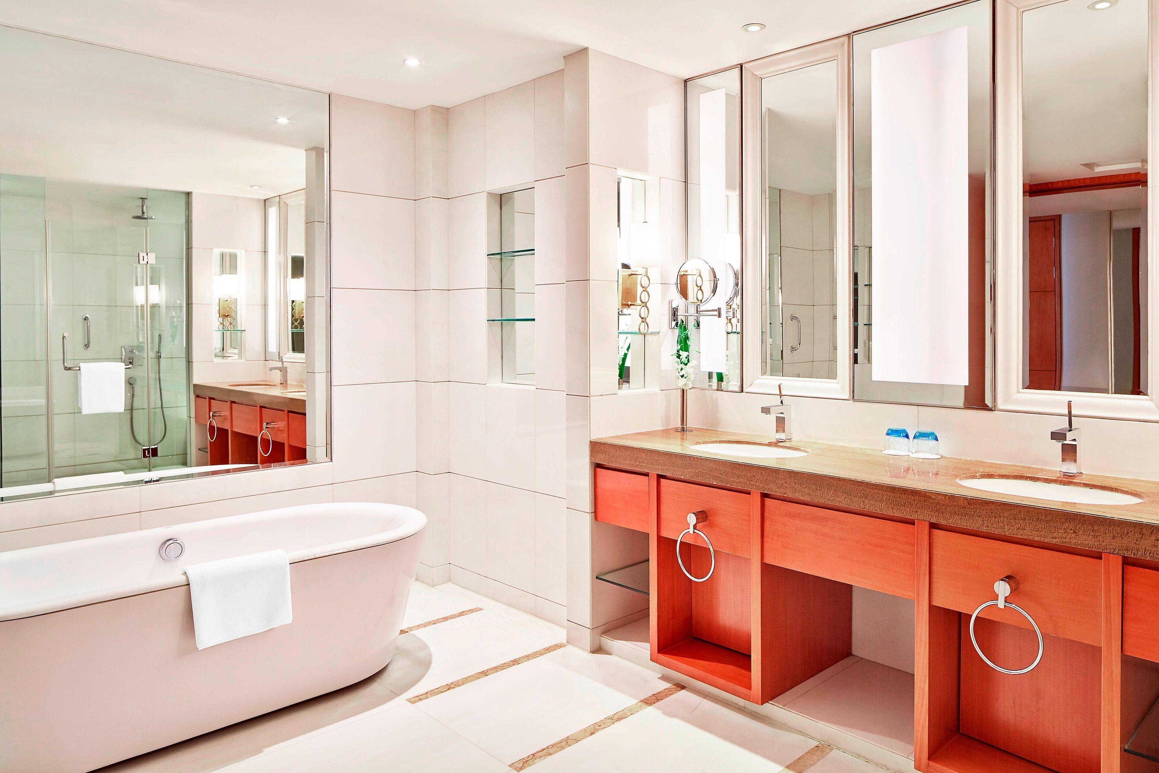 Une salle de bain moderne avec une baignoire sur pieds, deux vasques et un grand miroir.