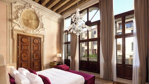 A bedroom with a large bed, wooden wardrobe, and a chandelier.