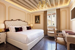 Habitación de hotel con una cama grande, un escritorio, una silla y vistas al exterior.
