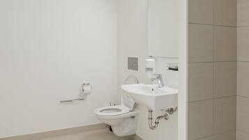 Een moderne badkamer met toilet, wastafel en spiegel.