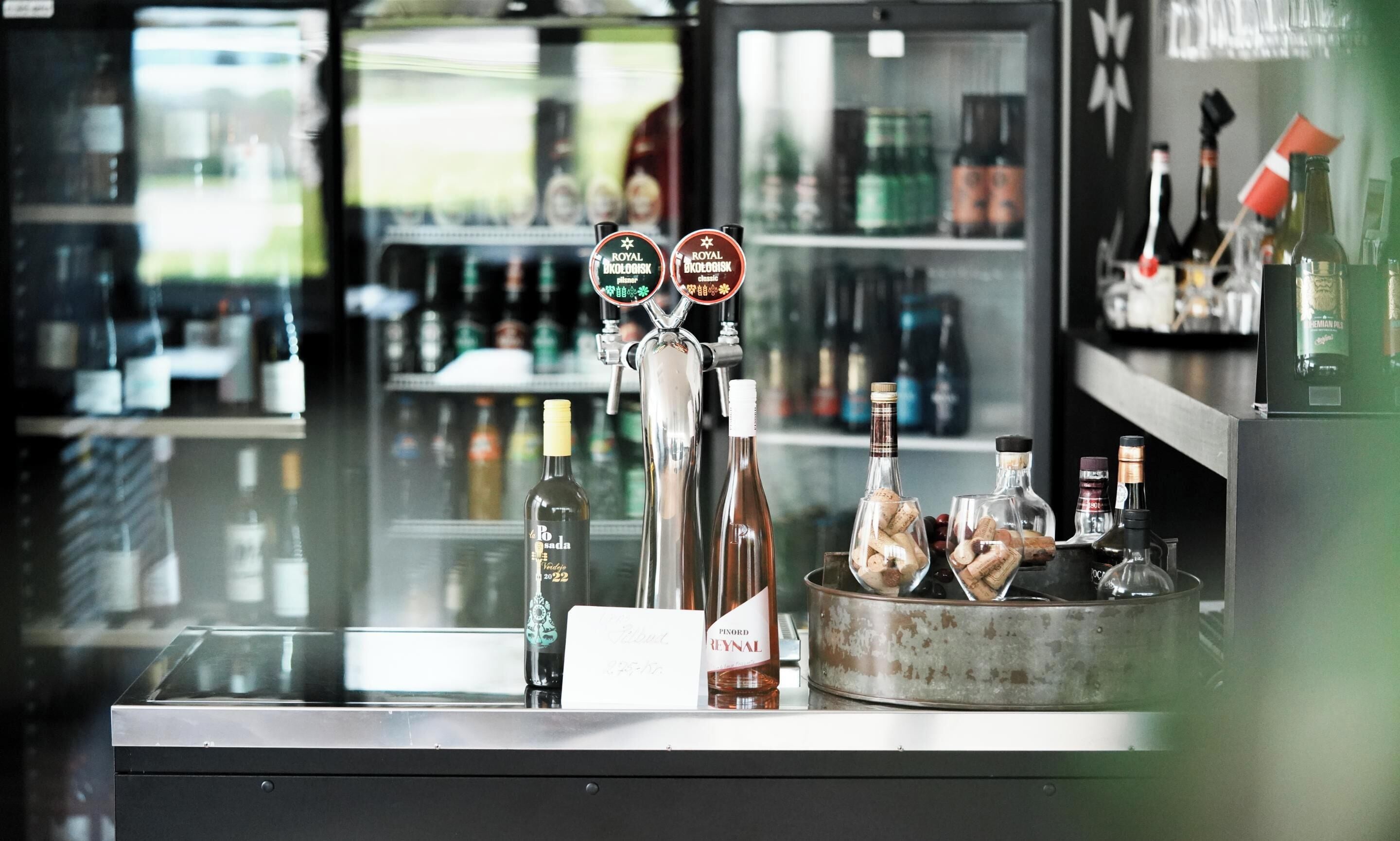 A bar counter with a selection of bottles and a tap labeled "Royal Biodogsk".