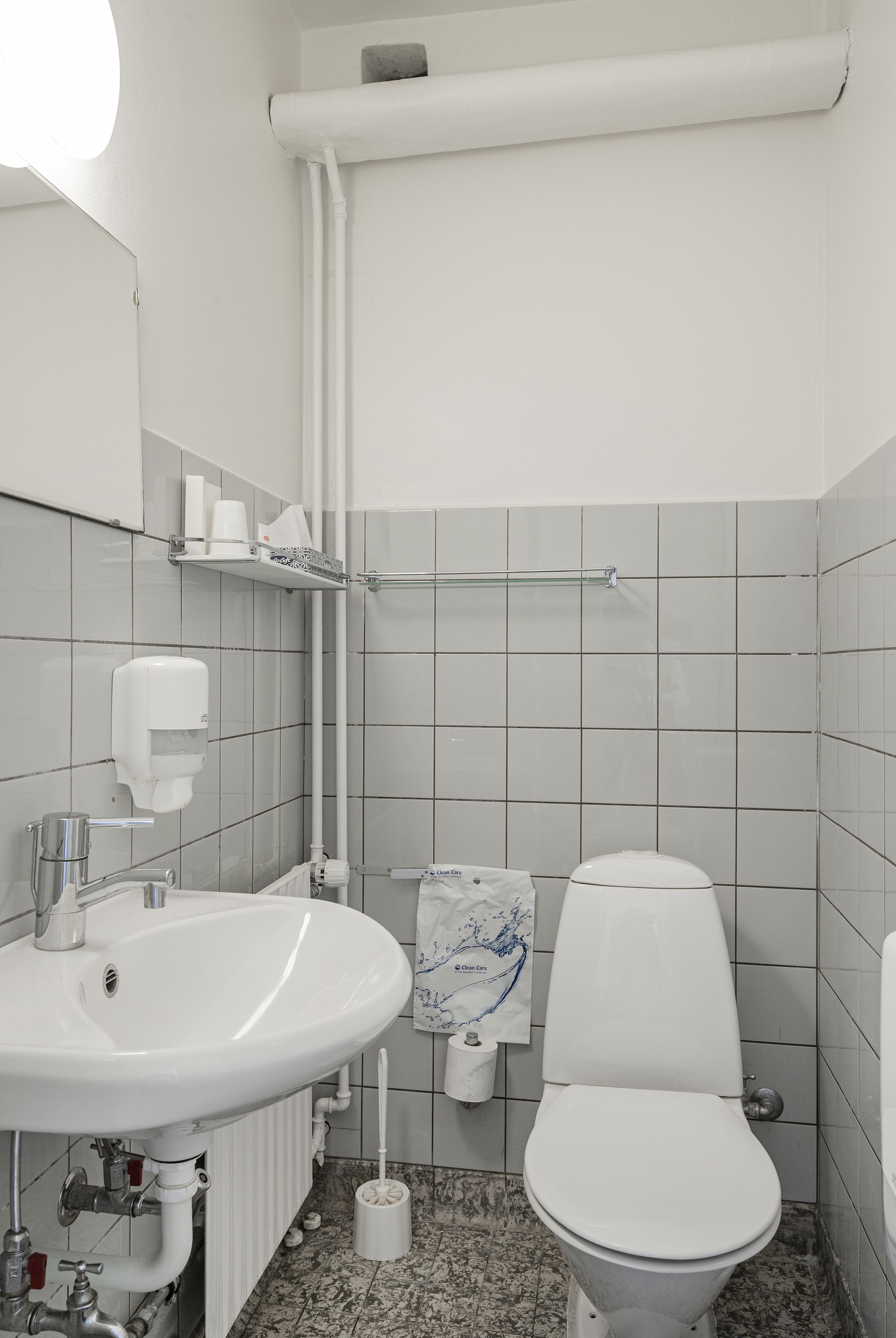 Une salle de bain avec un lavabo blanc, des toilettes et une serviette accrochée au mur.