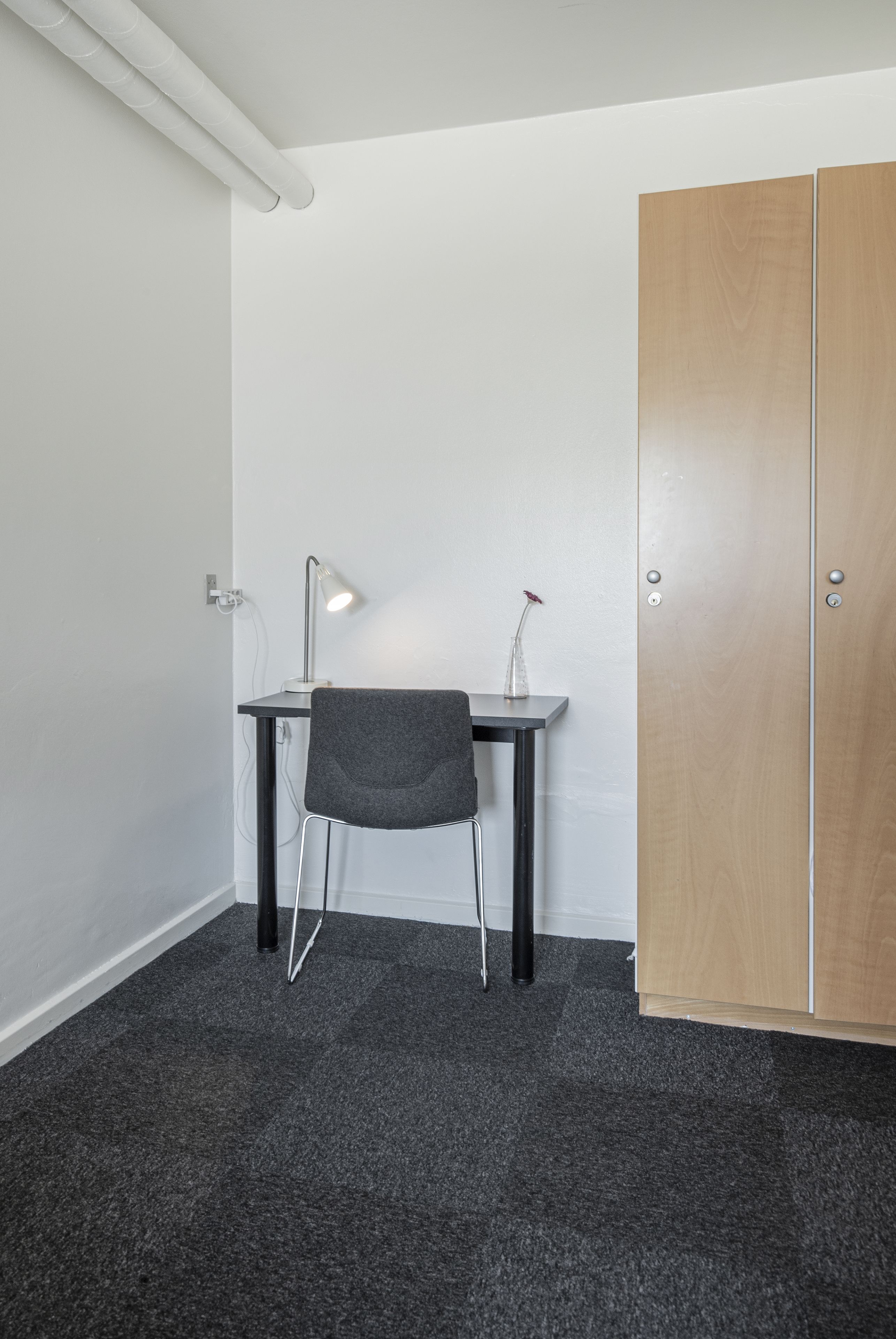 A small office space with a desk, chair, and a wardrobe.