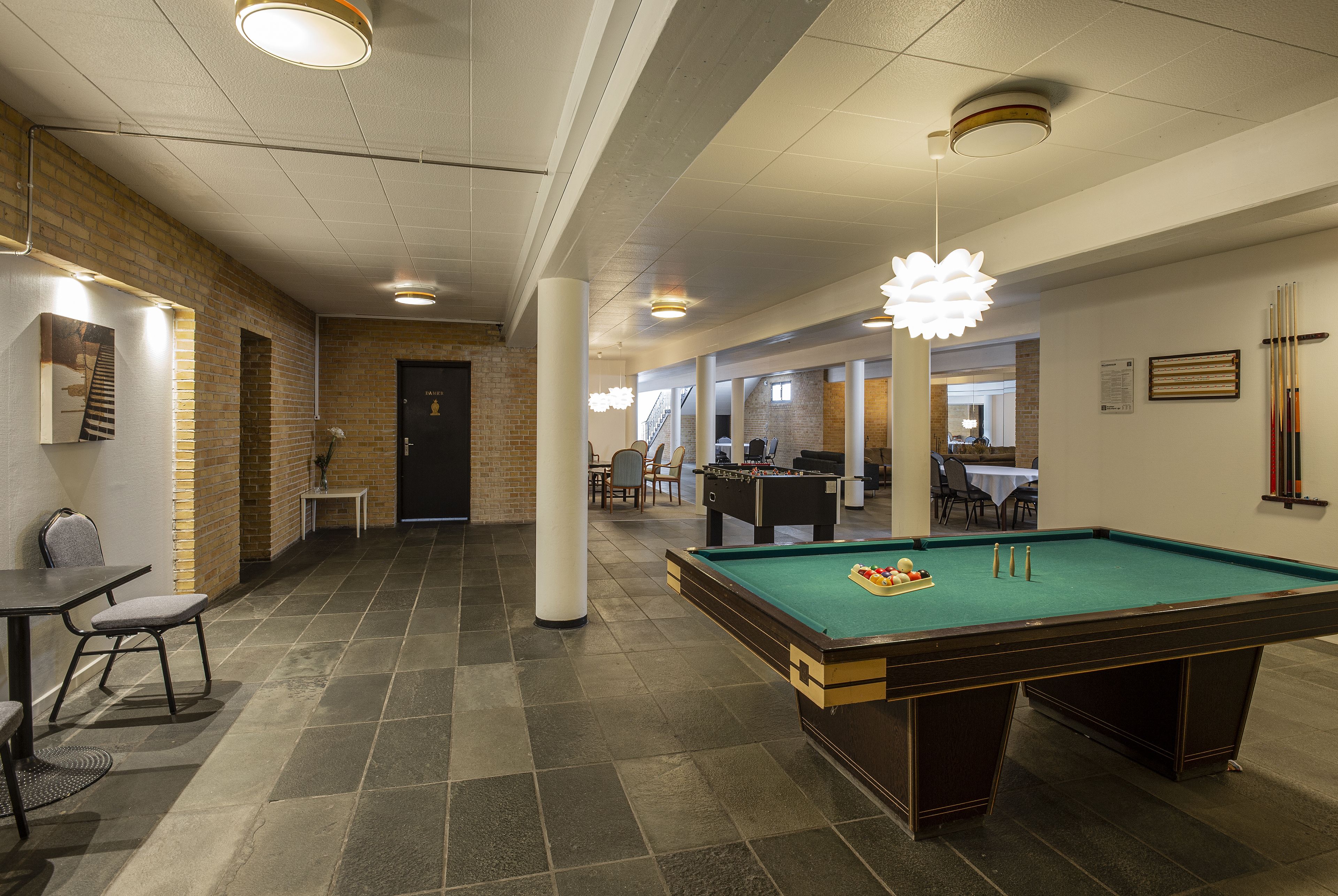 A billiards table in a room with a brick wall and a pool table.