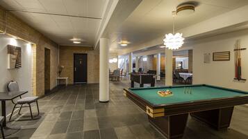 A billiards table in a room with a brick wall and a pool table.