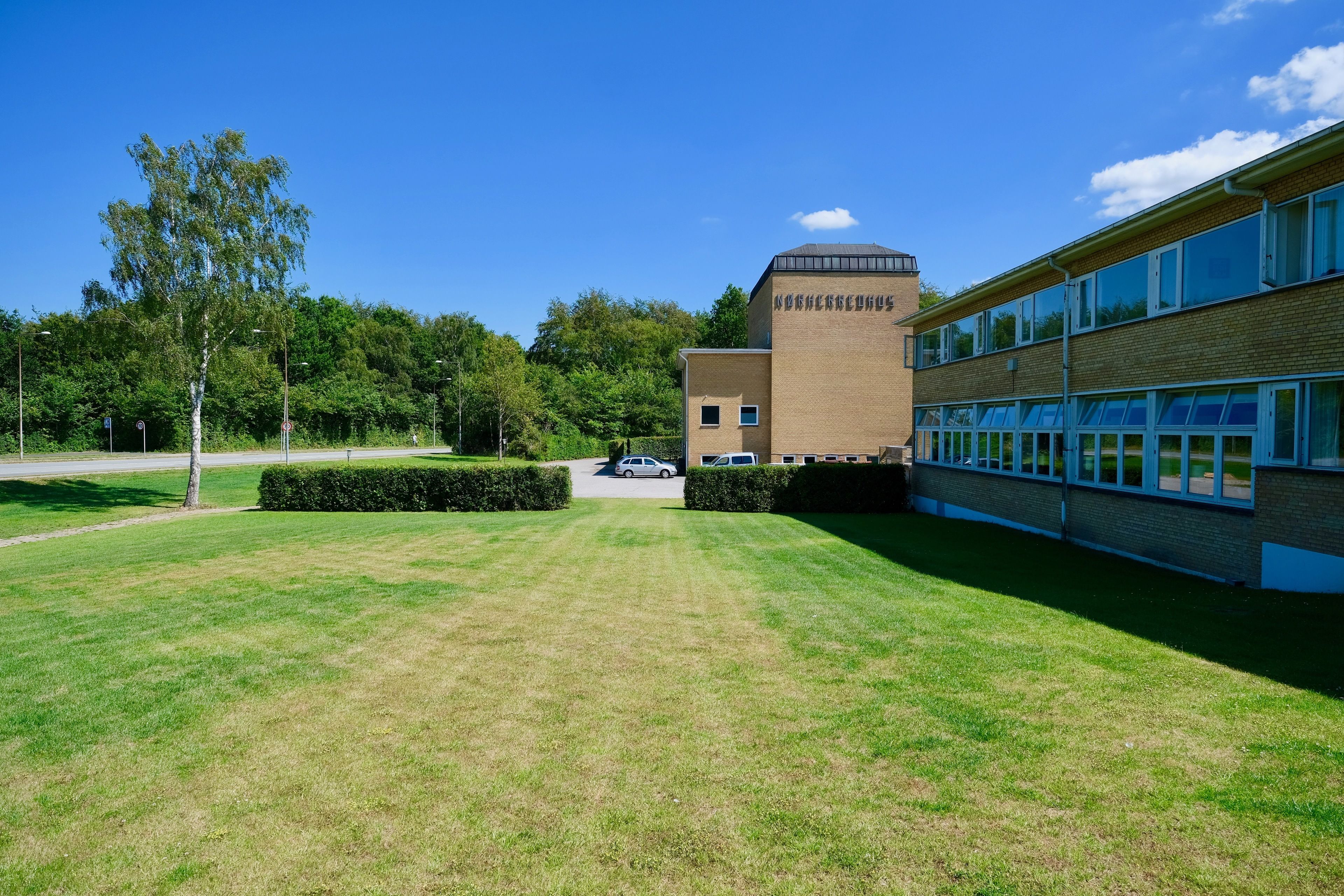 A building with a brick facade and a dome, surrounded by a well-maintained lawn and trees.