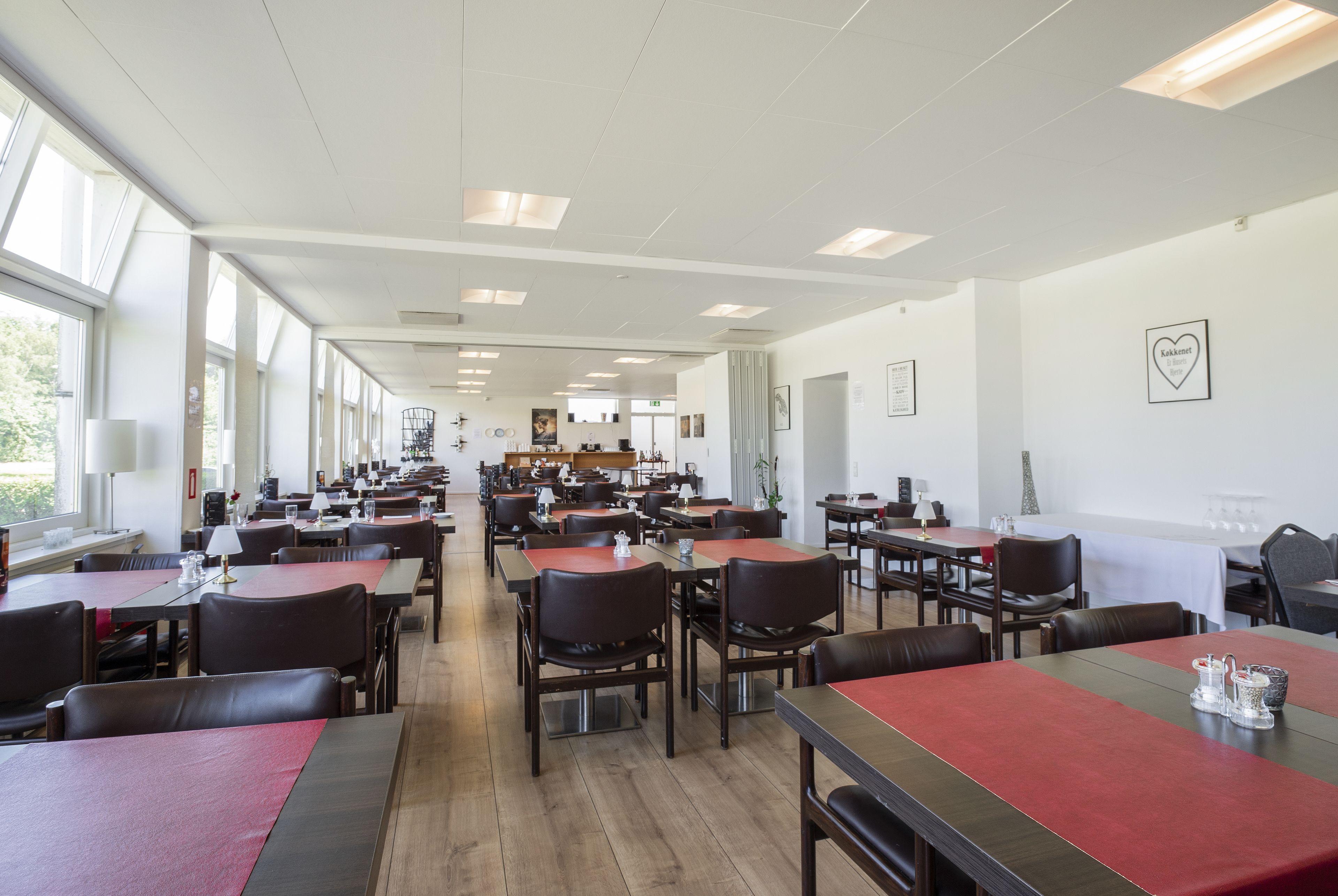 A spacious dining area with multiple tables and chairs, large windows, and a clean, modern interior.