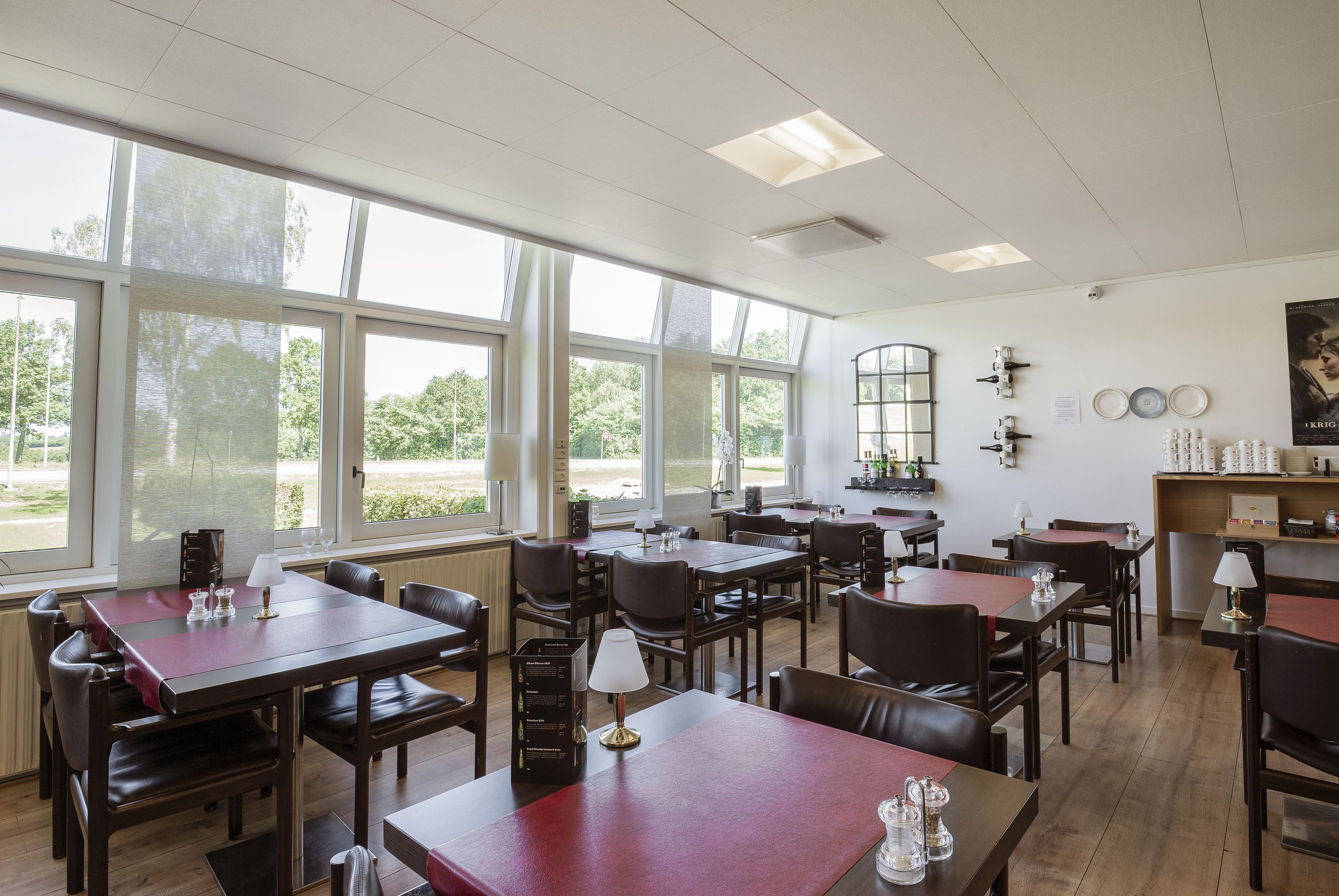 A restaurant with multiple tables and chairs, large windows, and a view of the outdoors.