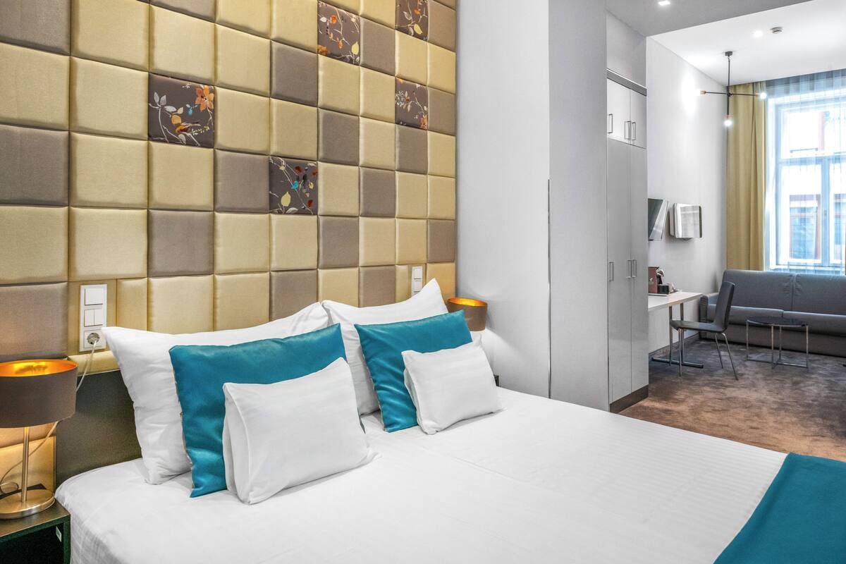 A hotel room with a large bed, a desk, and a chair.