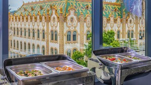 A buffet area with multiple serving stations and a view of a historic building with ornate architecture. - Hotel President Budapest, Affiliated by Meliá (Budapest)