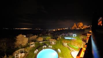 Relax by the illuminated pool surrounded by lush landscaping and a unique rock formation.